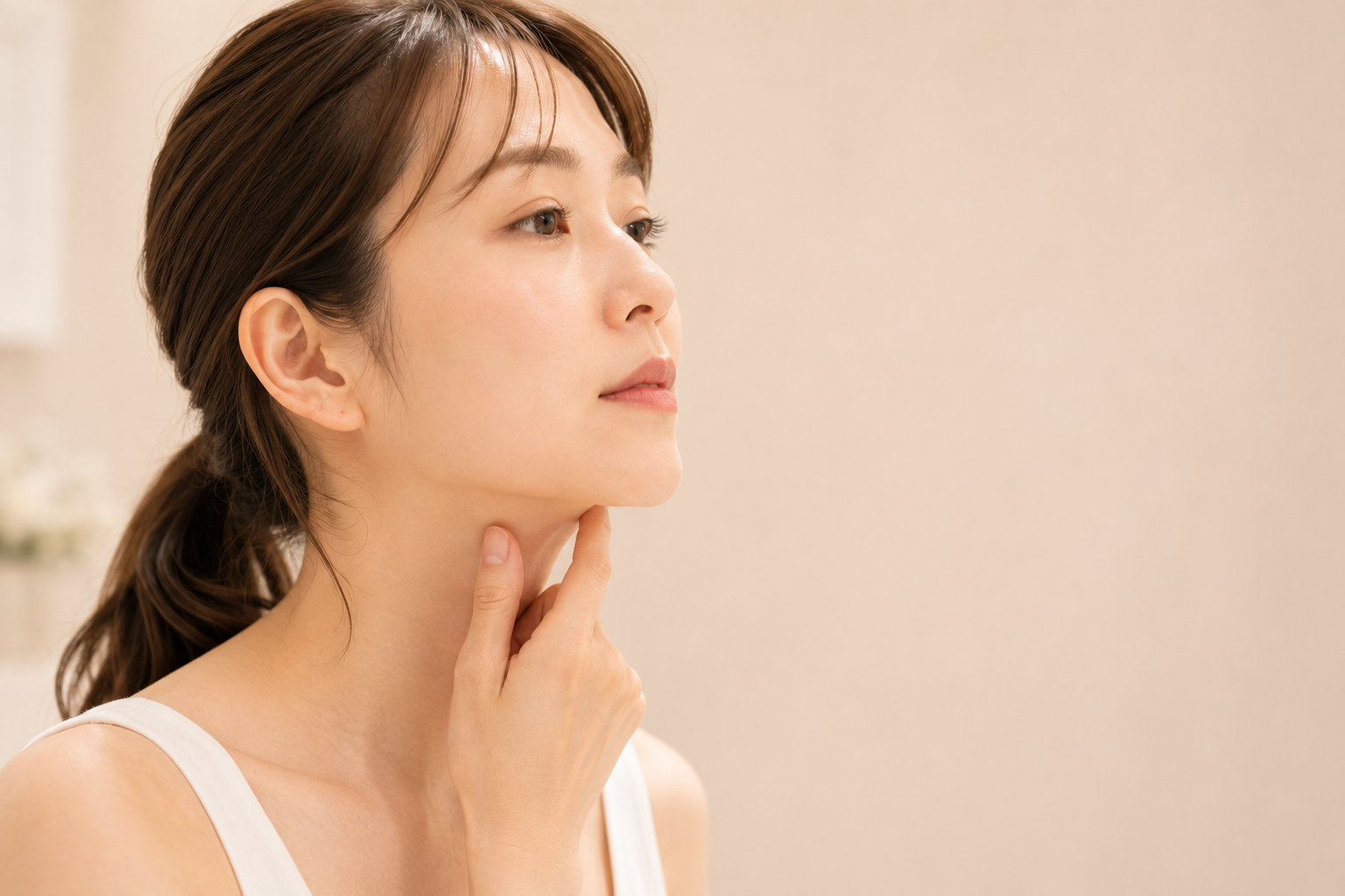 フェイスラインに触れる女性